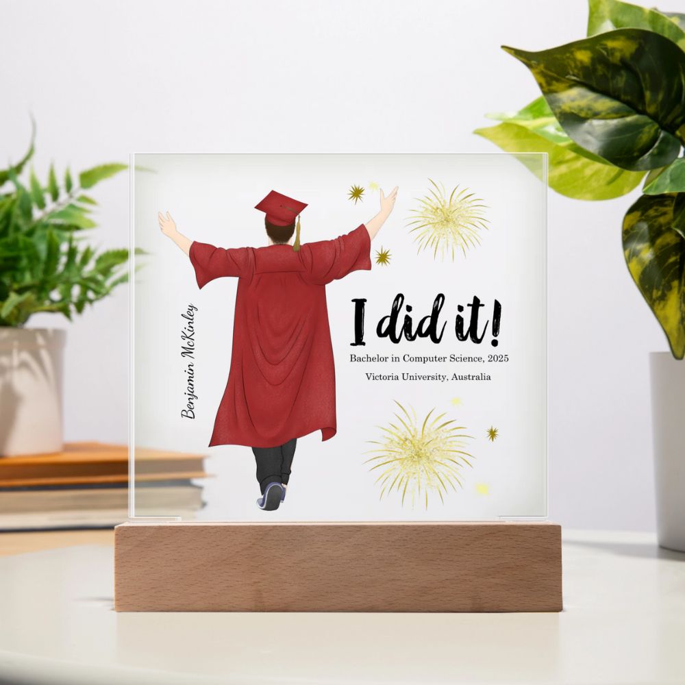Graduation-themed decorative plaque with a person in a red gown and cap, 'I did it!' text, and fireworks on a white background.