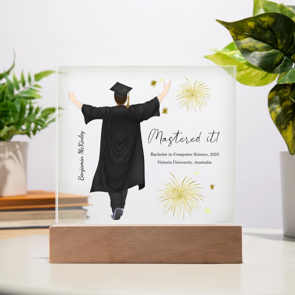 Graduation-themed decorative plaque with a person in a cap and gown, 'Mastered it!' text, and fireworks design on a white background.